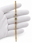 Gold-tone bracelet with three square purple, green and red decorative accents framed by clear-looking stones, double-row chain detailing and a clasp closure.