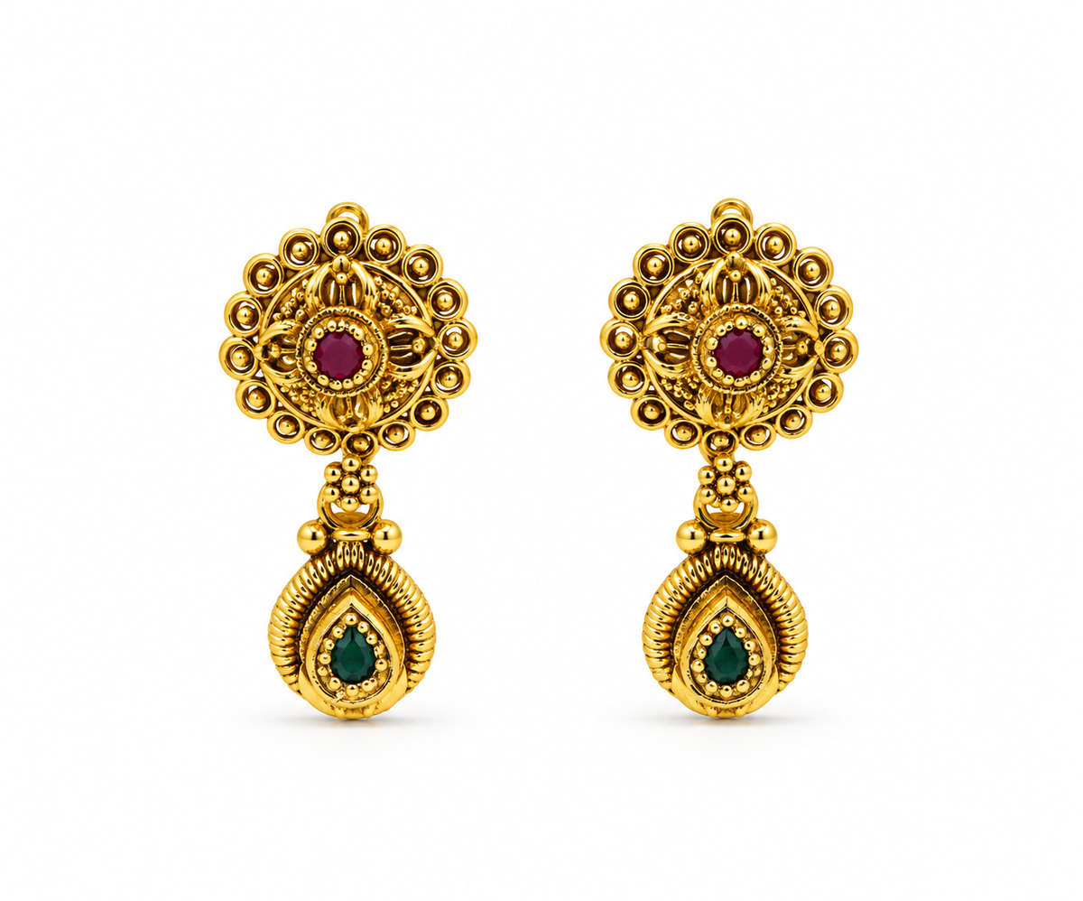 Gold-tone floral pendant necklace set displayed on white jewellery stands, featuring green and magenta-pink accents, a beaded chain, and matching earrings with green teardrop-shaped drops.