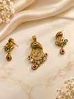 Gold-tone ornamental pendant and matching drop earrings displayed on a cream background, featuring intricate golden patterns, magenta-pink accents, green teardrop-shaped drops, and white decorative details.