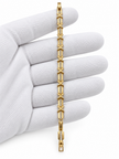 Gold-tone bracelet with blue, pink, green and clear square-shaped accents, decorative links, a lobster-style clasp and an extension chain, held against a white background.