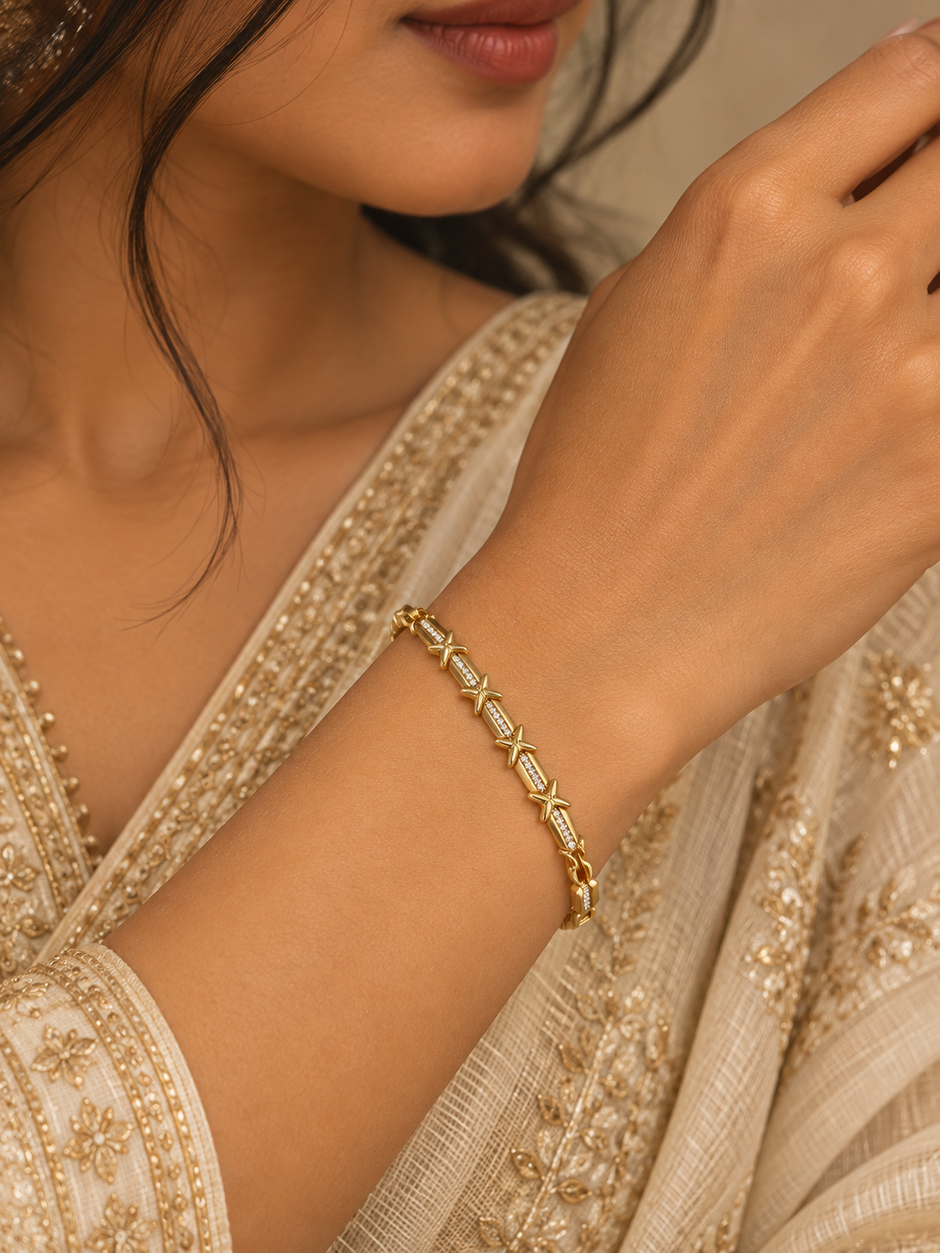 Gold-tone bracelet with blue, pink, green and clear square-shaped accents, decorative links, a lobster-style clasp and an extension chain, held against a white background.