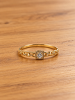 Gold-tone bracelet with a square-shaped central motif, large clear faceted centrepiece, surrounding rows of small clear decorative stones and an intricate openwork linked band.