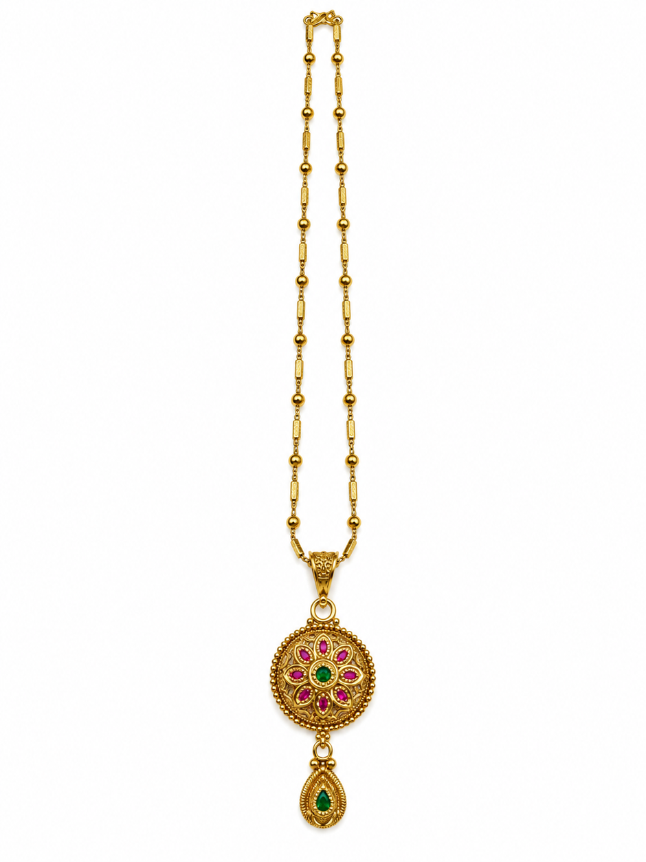 Gold-tone floral pendant necklace set displayed on white jewellery stands, featuring green and magenta-pink accents, a beaded chain, and matching earrings with green teardrop-shaped drops.