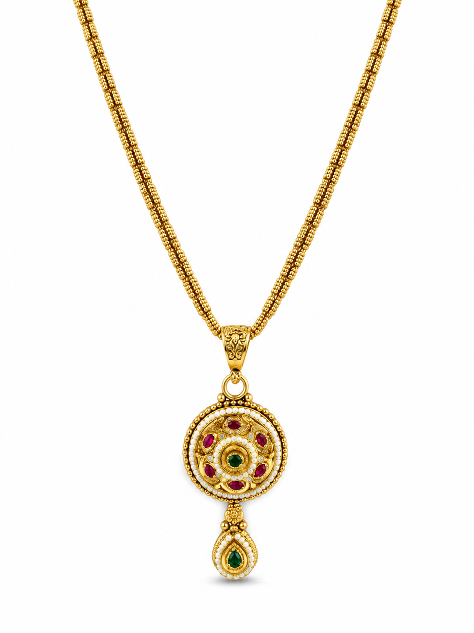 Gold-tone floral halo necklace set displayed on white jewellery stands, featuring a round pendant with green and magenta-pink accents, a decorative beaded chain, and matching earrings with green teardrop-shaped drops.