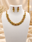 Traditional gold-tone floral necklace set with matching dangling earrings, featuring magenta and green accents, ivory-white bead-like details and intricate ornamental motifs.