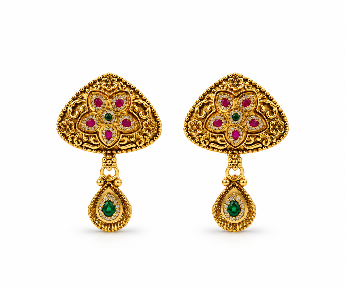 Gold-tone floral temple necklace set displayed on white jewellery stands, featuring a triangular ornamental pendant with green and magenta-pink accents, a beaded chain, and matching earrings with green teardrop-shaped drops.