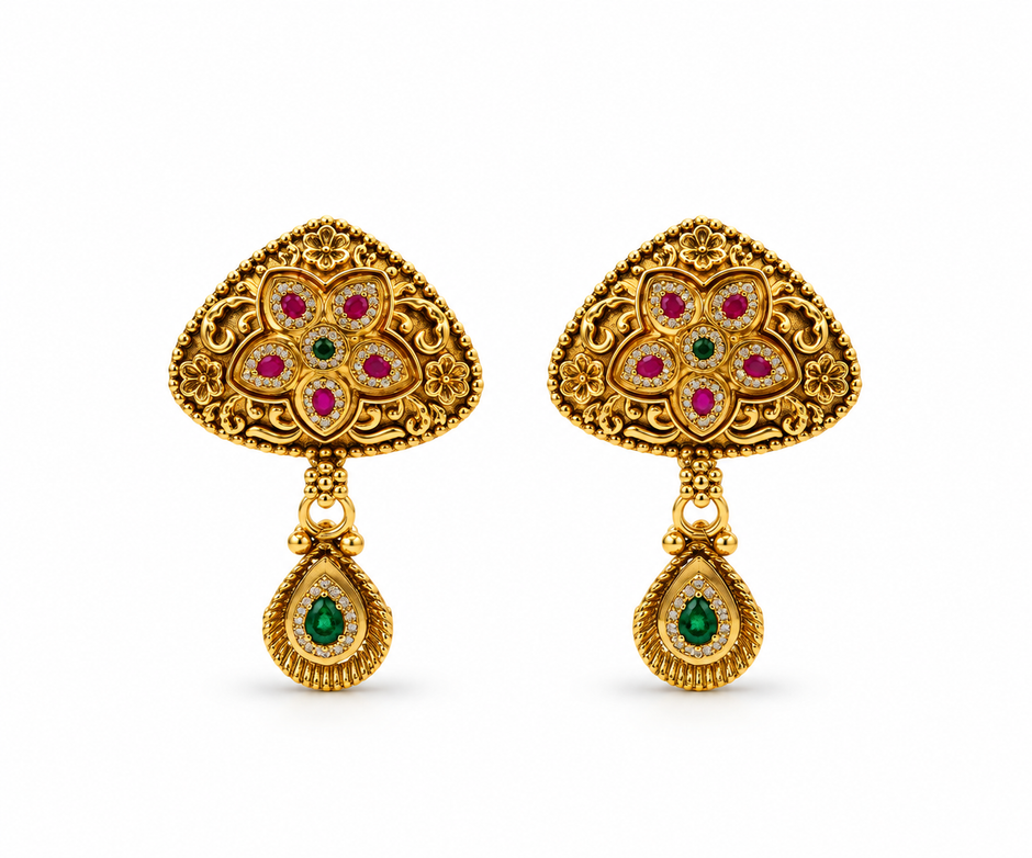Gold-tone floral temple necklace set displayed on white jewellery stands, featuring a triangular ornamental pendant with green and magenta-pink accents, a beaded chain, and matching earrings with green teardrop-shaped drops.