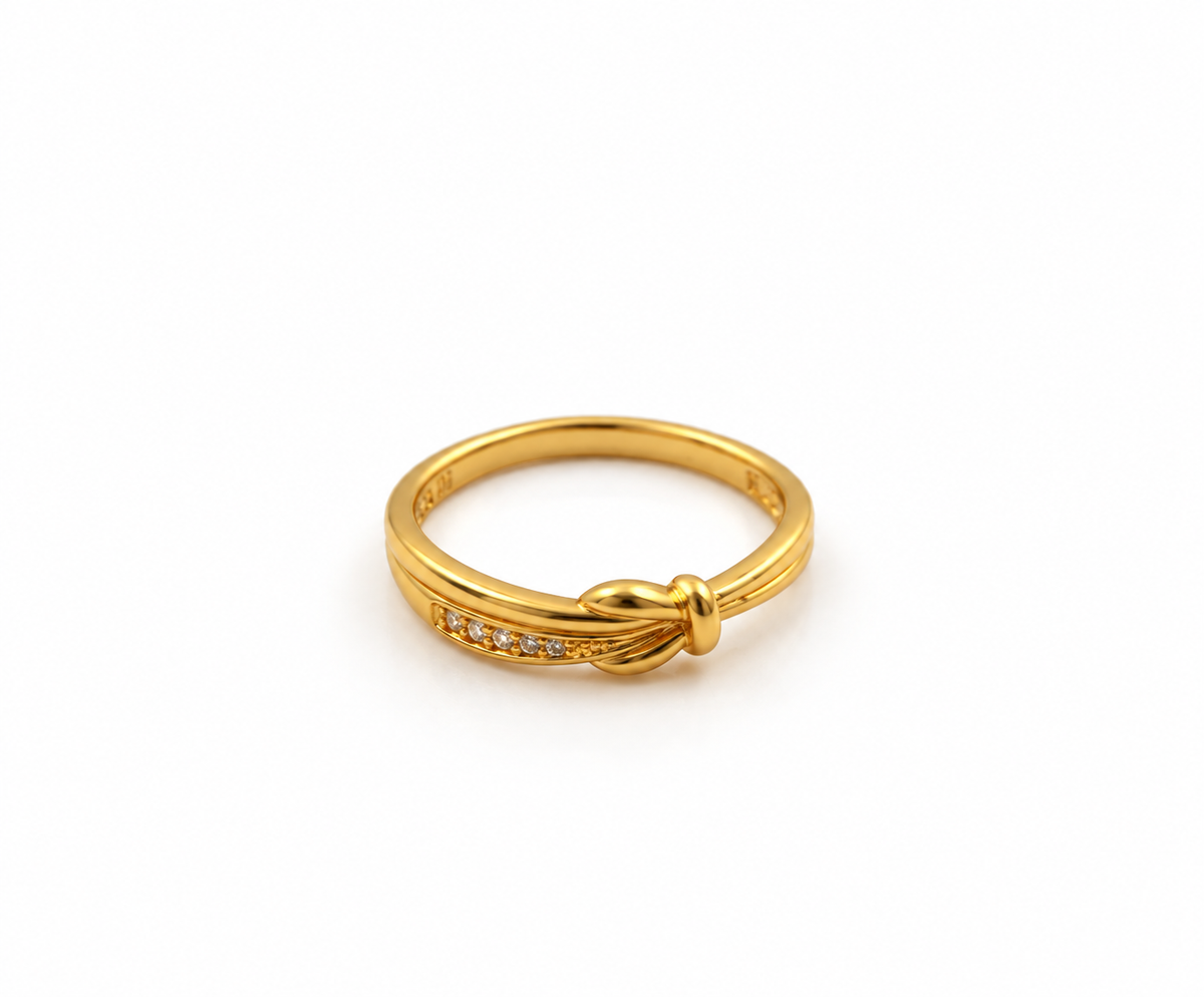 Gold-tone knot ring featuring intertwined curved loops, a row of small clear stones and dark accents, shown on a finger and from the side.