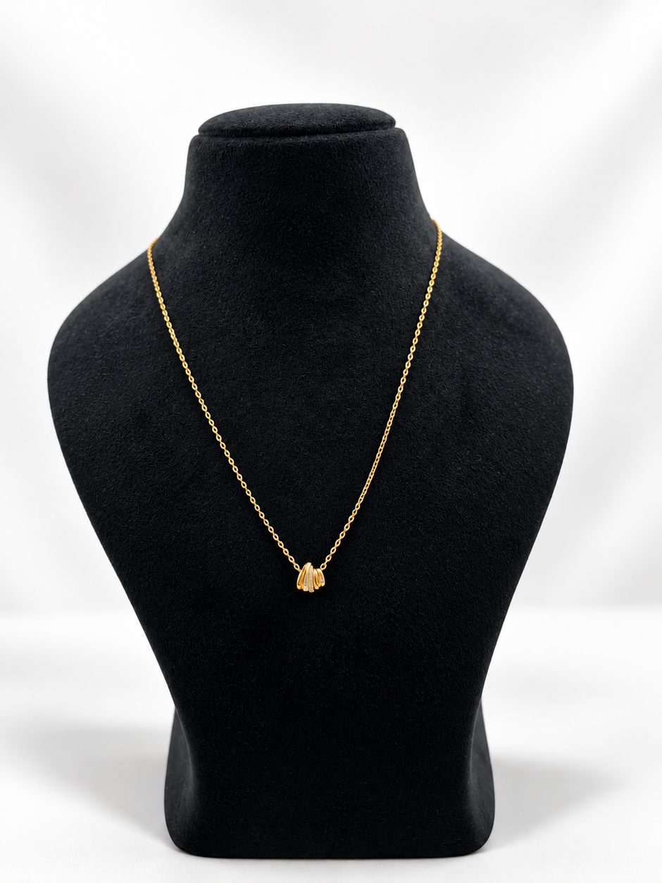 Gold-tone necklace with a fine linked chain and a small layered curved pendant featuring clear reflective stones, displayed on a black jewellery bust and a white gloved hand.