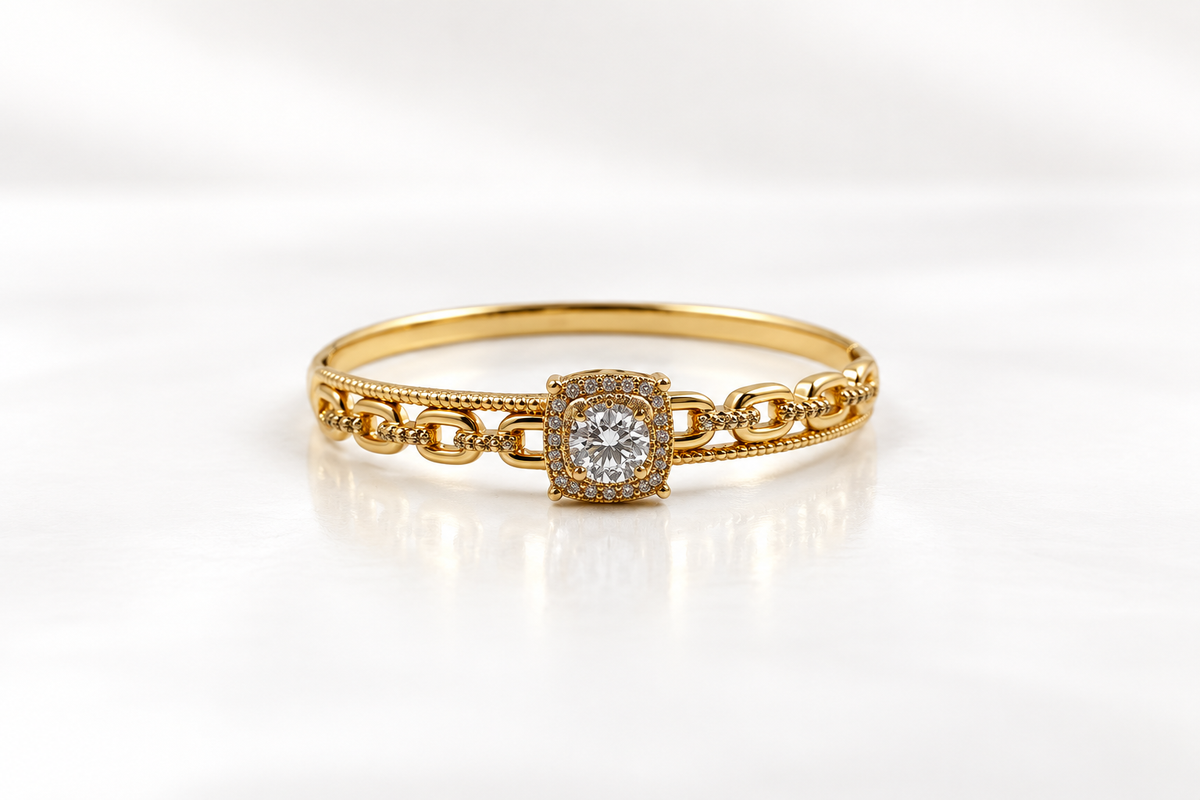Gold-tone bracelet with a square-shaped central motif, large clear faceted centrepiece, surrounding rows of small clear decorative stones and an intricate openwork linked band.