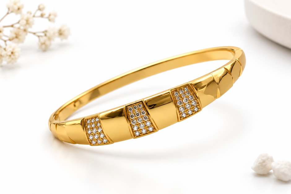 Gold-tone wide band bracelet displayed against a white background, featuring three rectangular front panels decorated with rows of clear accents and smooth golden sections.