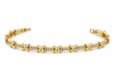 Gold-tone bracelet with blue, pink, green and clear square-shaped accents, decorative links, a lobster-style clasp and an extension chain, held against a white background.