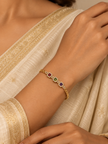 Gold-tone bracelet with three square purple, green and red decorative accents framed by clear-looking stones, double-row chain detailing and a clasp closure.