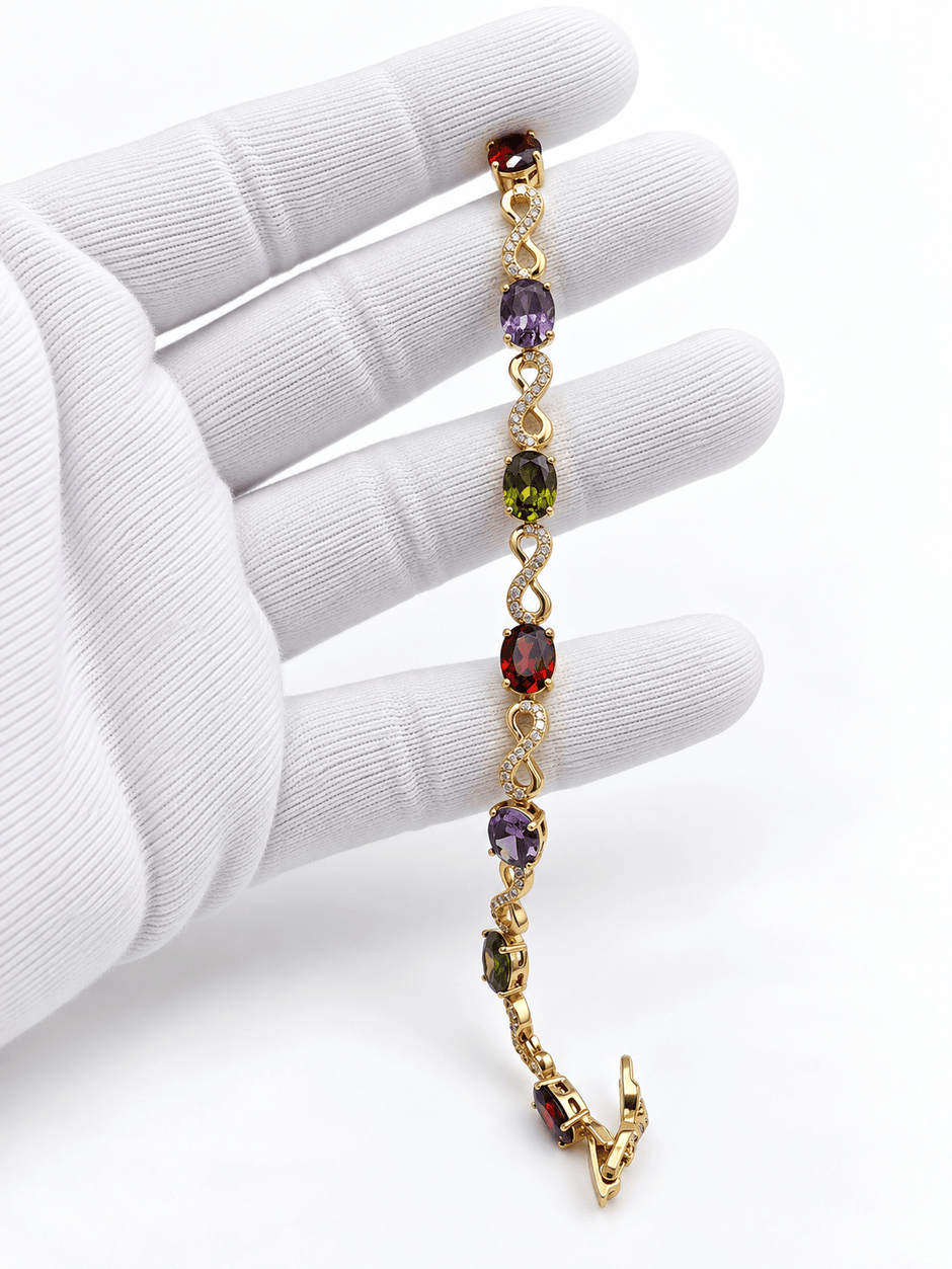 Golden-toned multicolor bracelet with red purple and green oval accents and clear decorative link details