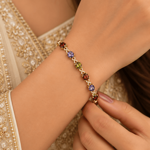Golden-toned multicolor bracelet with red purple and green oval accents and clear decorative link details