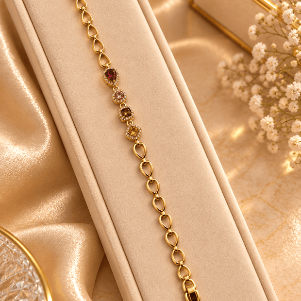Golden oval link bracelet with deep red pink and amber-brown coloured accents and clear decorative borders