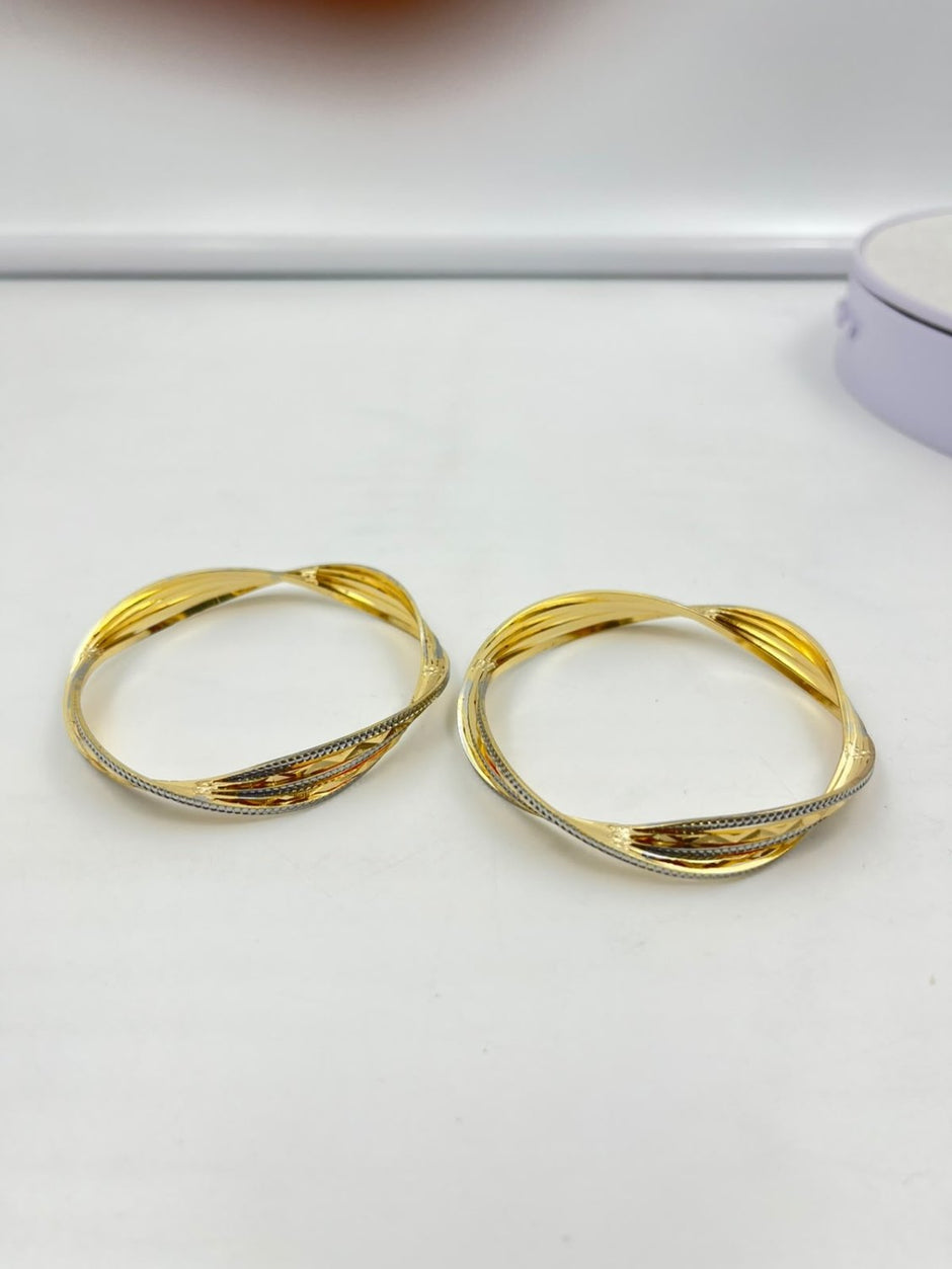 Pair of golden-toned twisted bangles with layered curved bands and contrasting textured detailing