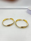 Pair of golden-toned twisted bangles with layered curved bands and contrasting textured detailing