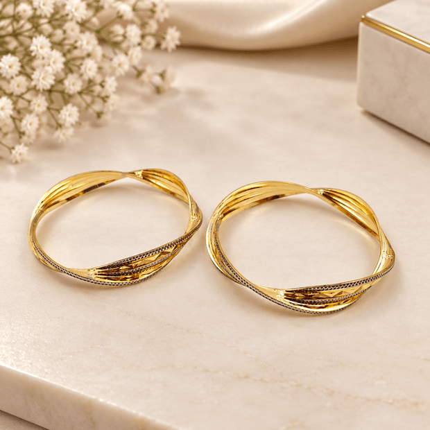 Pair of golden-toned twisted bangles with layered curved bands and contrasting textured detailing