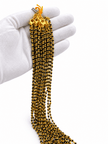 Black beaded necklace with small gold-tone connecting elements and a gold-tone clasp, displayed as an elongated chain on a white background and held in a white-gloved hand. - bhavmayi