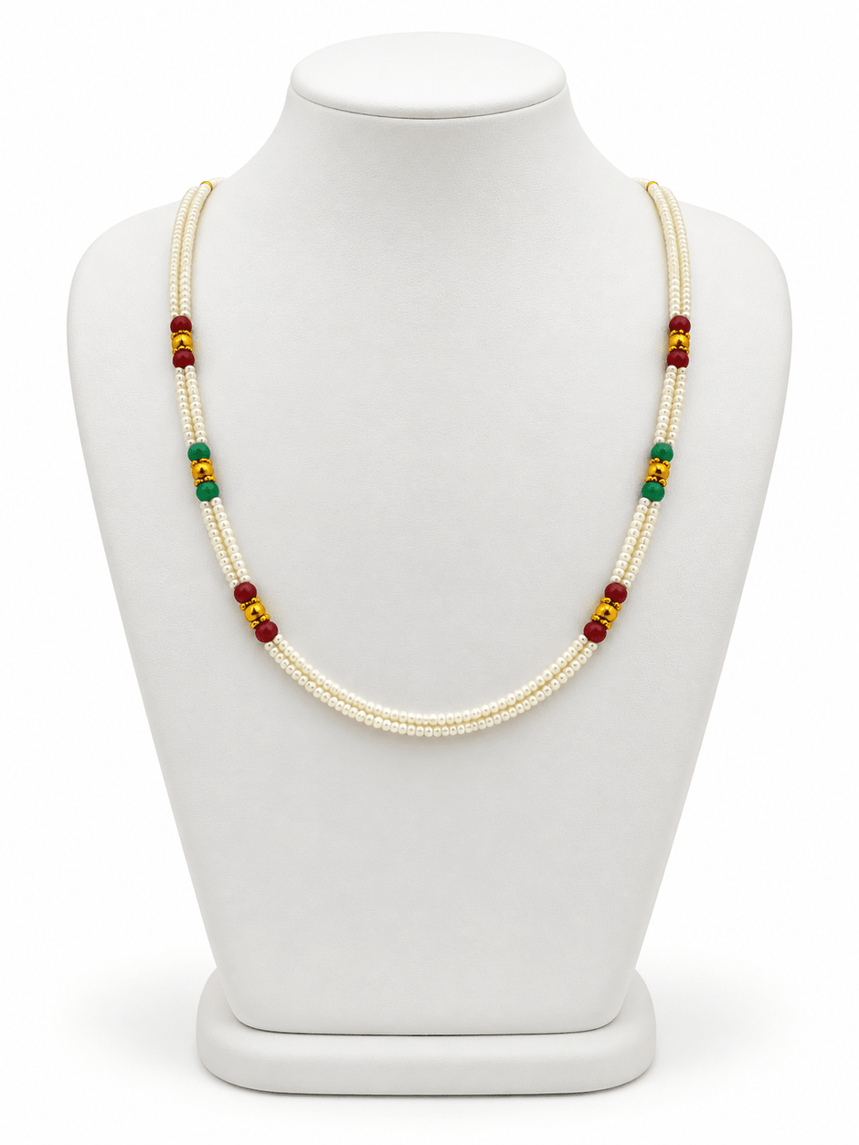 Double-strand white beaded necklace with deep red and green bead accents, decorative gold-tone elements and a gold-tone clasp displayed on a white necklace stand. - bhavmayi