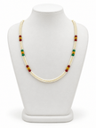 Double-strand white beaded necklace with deep red and green bead accents, decorative gold-tone elements and a gold-tone clasp displayed on a white necklace stand. - bhavmayi
