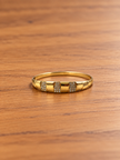 Gold-tone wide band bracelet displayed against a white background, featuring three rectangular front panels decorated with rows of clear accents and smooth golden sections.