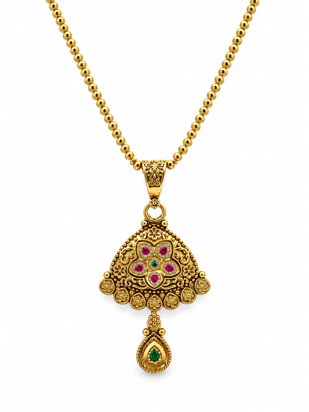 Gold-tone floral temple necklace set displayed on white jewellery stands, featuring a triangular ornamental pendant with green and magenta-pink accents, a beaded chain, and matching earrings with green teardrop-shaped drops.