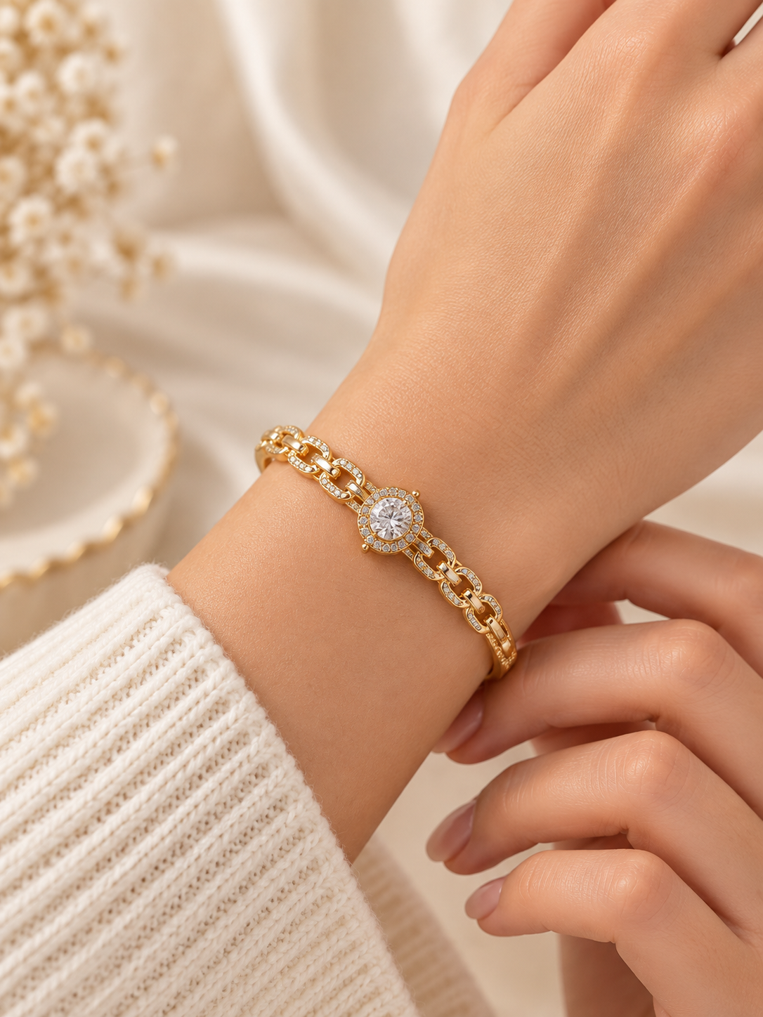 Gold-tone bracelet with a square-shaped central motif, large clear faceted centrepiece, surrounding rows of small clear decorative stones and an intricate openwork linked band.