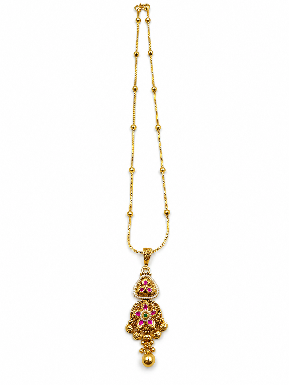 Gold-tone temple necklace set displayed on a white jewellery bust, featuring a decorative pendant with green and magenta accents, a beaded chain, and matching triangular drop earrings.