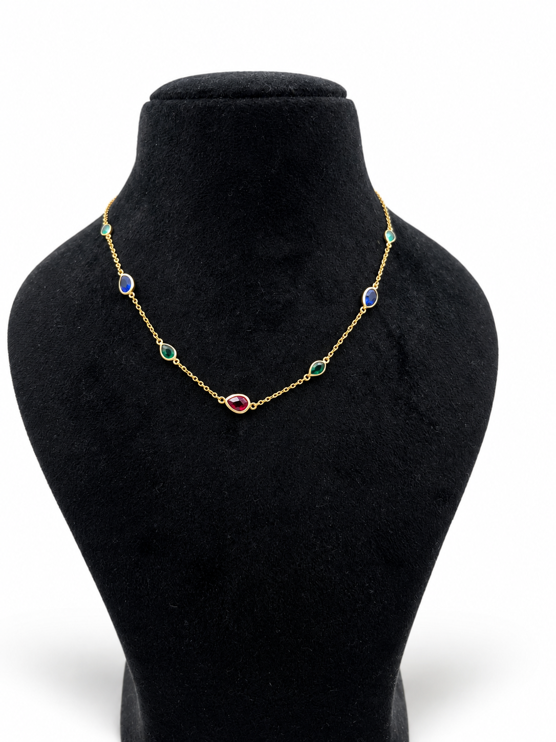 Gold-tone necklace and matching bracelet featuring delicate chains with spaced blue, teal green and burgundy red decorative accents, displayed on a model and separately.