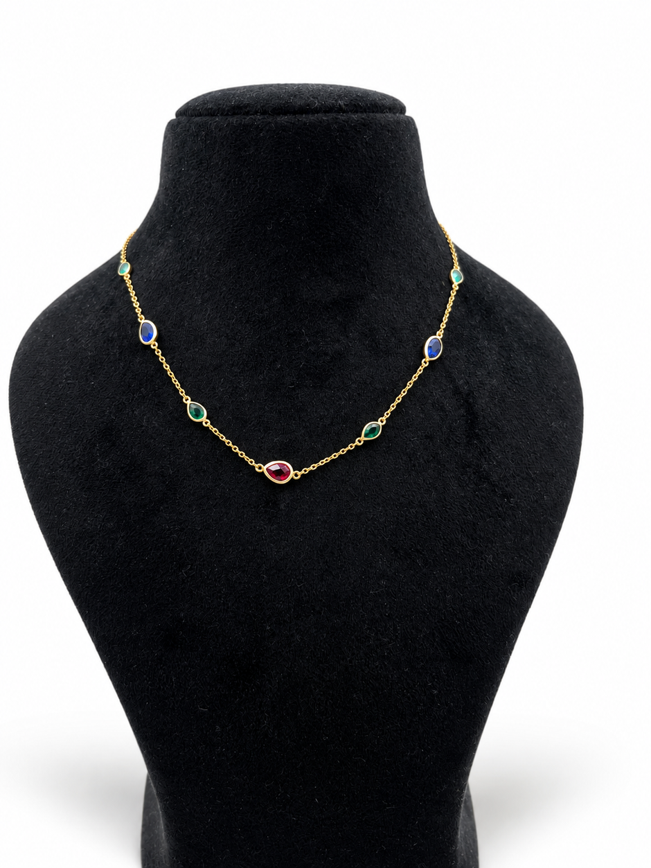 Gold-tone necklace and matching bracelet featuring delicate chains with spaced blue, teal green and burgundy red decorative accents, displayed on a model and separately.