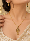 Gold-tone floral pendant necklace set displayed on white jewellery stands, featuring green and magenta-pink accents, a beaded chain, and matching earrings with green teardrop-shaped drops.