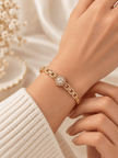 Gold-tone bracelet with a square-shaped central motif, large clear faceted centrepiece, surrounding rows of small clear decorative stones and an intricate openwork linked band. - bhavmayi
