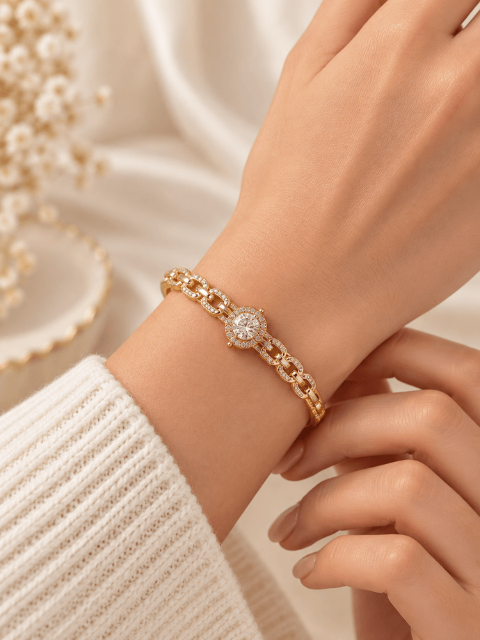 Gold-tone bracelet with a square-shaped central motif, large clear faceted centrepiece, surrounding rows of small clear decorative stones and an intricate openwork linked band. - bhavmayi