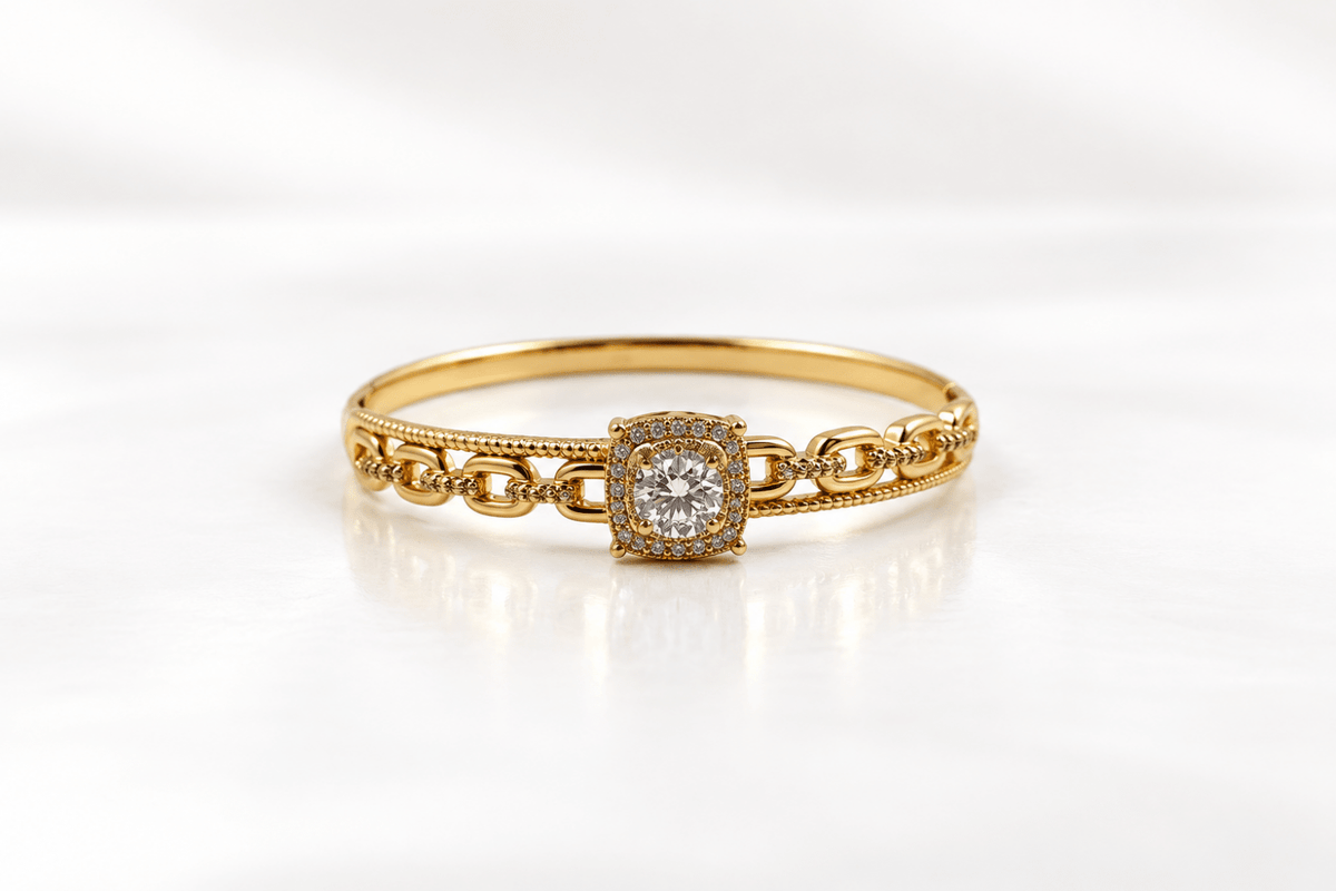 Gold-tone bracelet with a square-shaped central motif, large clear faceted centrepiece, surrounding rows of small clear decorative stones and an intricate openwork linked band. - bhavmayi