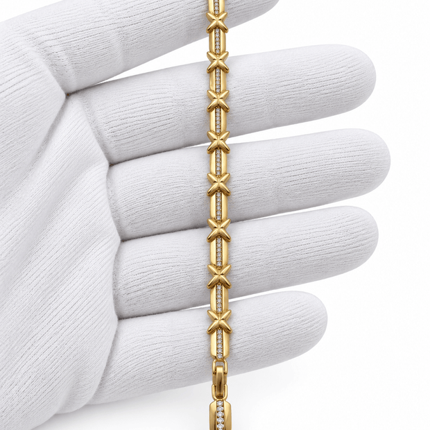 Golden bracelet featuring repeated X-shaped motifs, clear accent detailing and structured clasp links