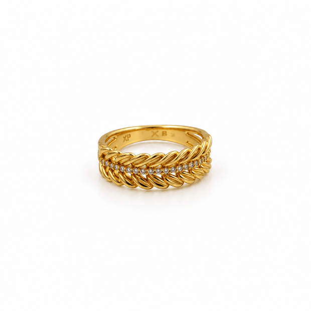 Gold-tone decorative ring with overlapping diagonal leaf-like curves and a central row of small clear stones, shown on a white background and worn on a finger. - bhavmayi