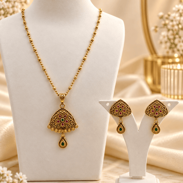 Gold-tone floral temple necklace set with green and magenta accents, featuring a pendant and matching drop earrings.