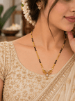 Gold-tone mangalsutra necklace with black bead chain, symmetrical leaf-shaped centerpiece, clear stone embellishments and a decorative central drop detail, displayed on a white background. - bhavmayi
