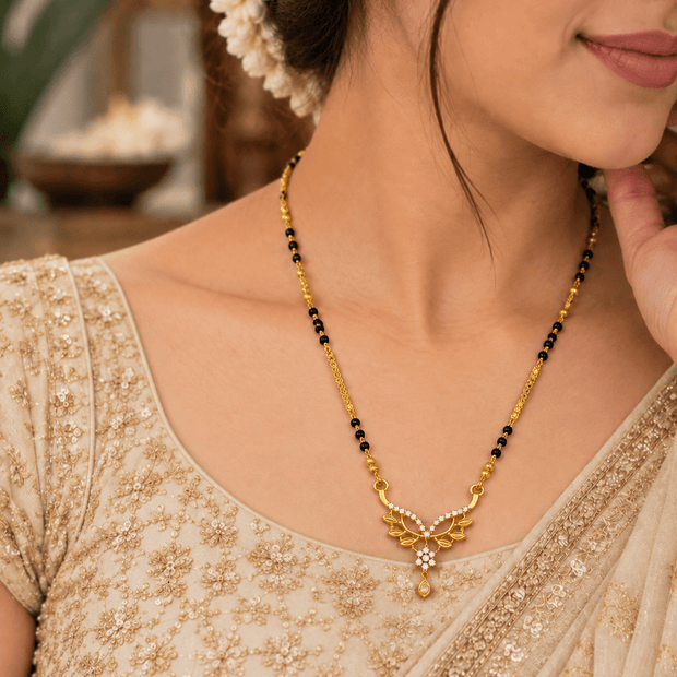 Bhavmayi floral mangalsutra necklace with a gold-tone chain, black bead accents, white stone detailing.