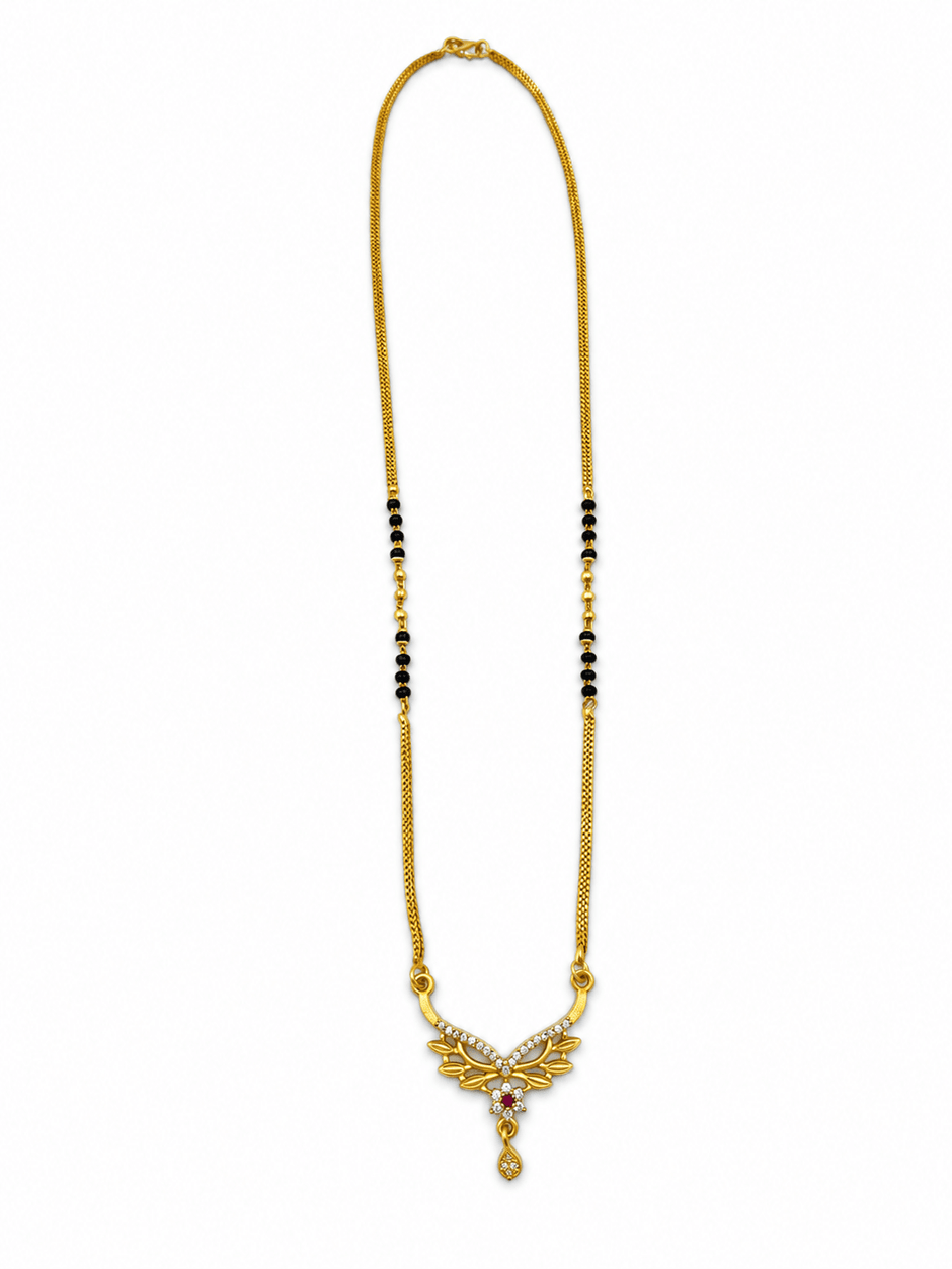 Gold-tone mangalsutra necklace with black beads, symmetrical floral leaf-shaped centerpiece, clear decorative stones, red center accent, and dangling teardrop pendant on a white background. - bhavmayi