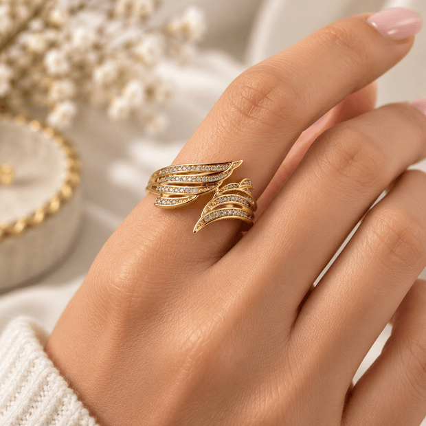 Golden statement ring with layered leaf-like curved bands and rows of clear accent details