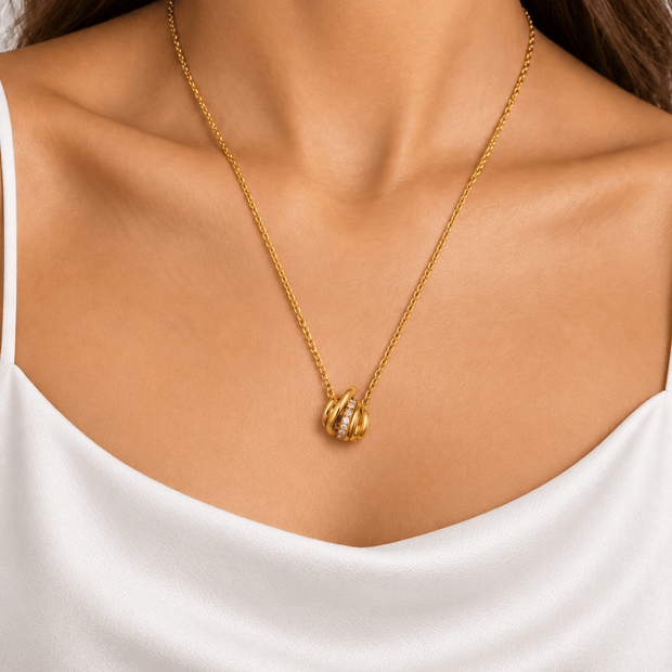 Gold-tone pendant necklace with fine linked chain and overlapping curved loop pendant with clear accents