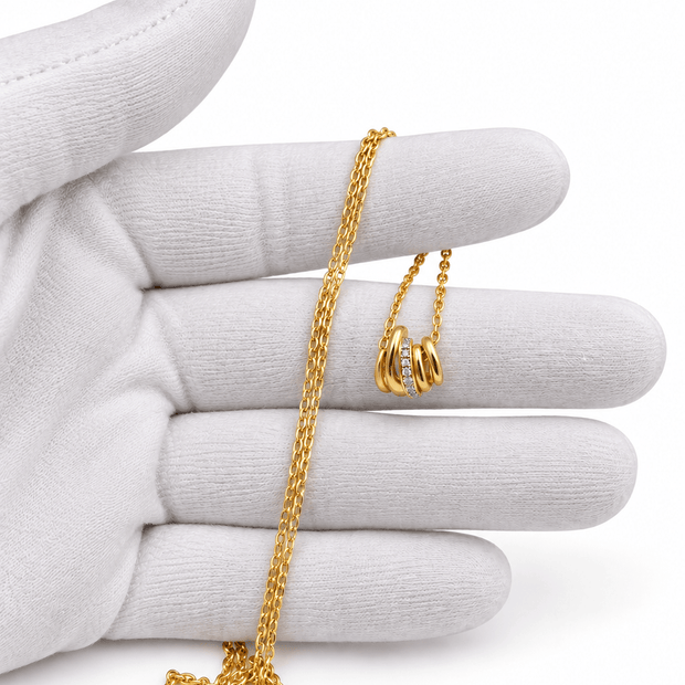 Gold-tone pendant necklace with fine linked chain and overlapping curved loop pendant with clear accents