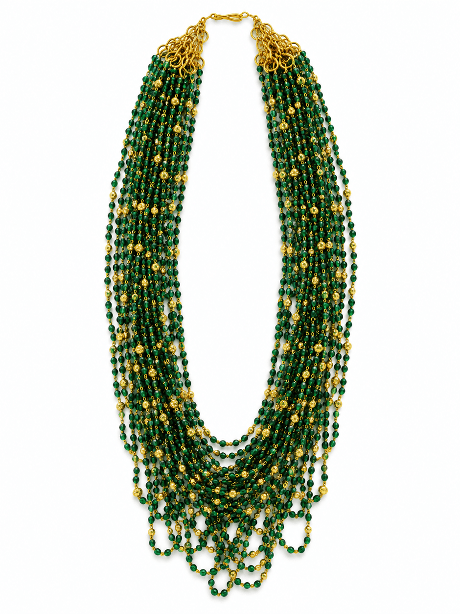 Green beaded necklace with small gold-tone connecting elements and a gold-tone clasp, displayed in a rounded elongated shape on a white jewellery display and against an elegant neutral background. - bhavmayi
