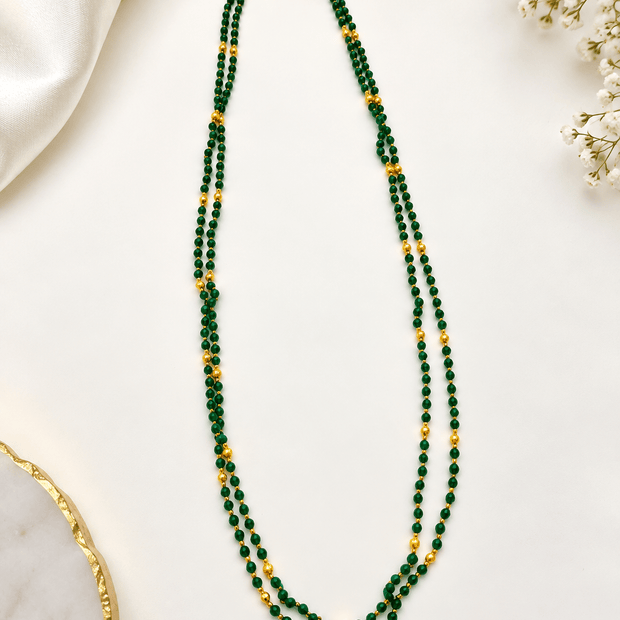 Double strand necklace featuring deep-green round beads, spaced gold-tone accents, displayed on a white background.