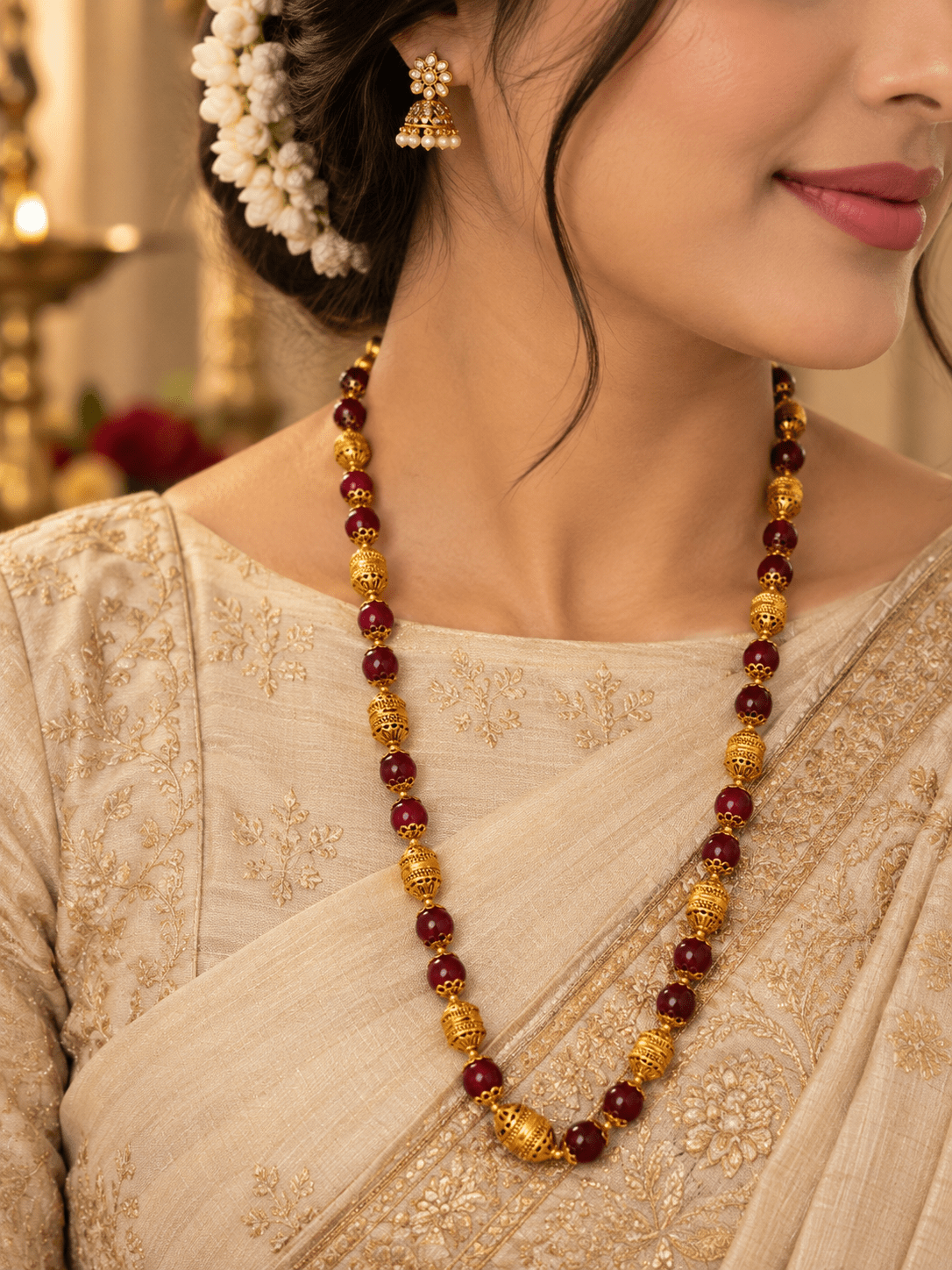 Long maroon beaded necklace with glossy rounded beads, ornate gold-tone barrel-shaped beads, floral-style bead caps and a hook-style clasp, shown from two angles. - bhavmayi