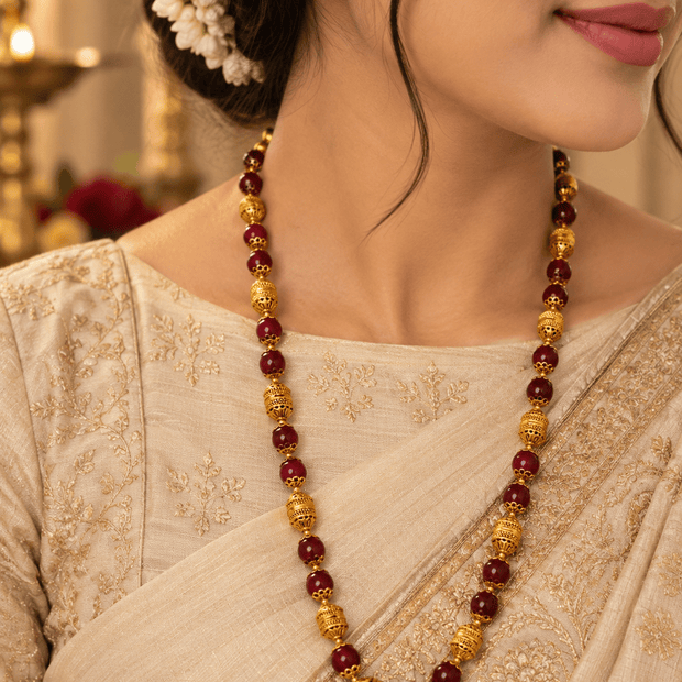 Bhavmayi maroon bead necklace with ornate gold-tone spherical accents and matching jhumka earrings.