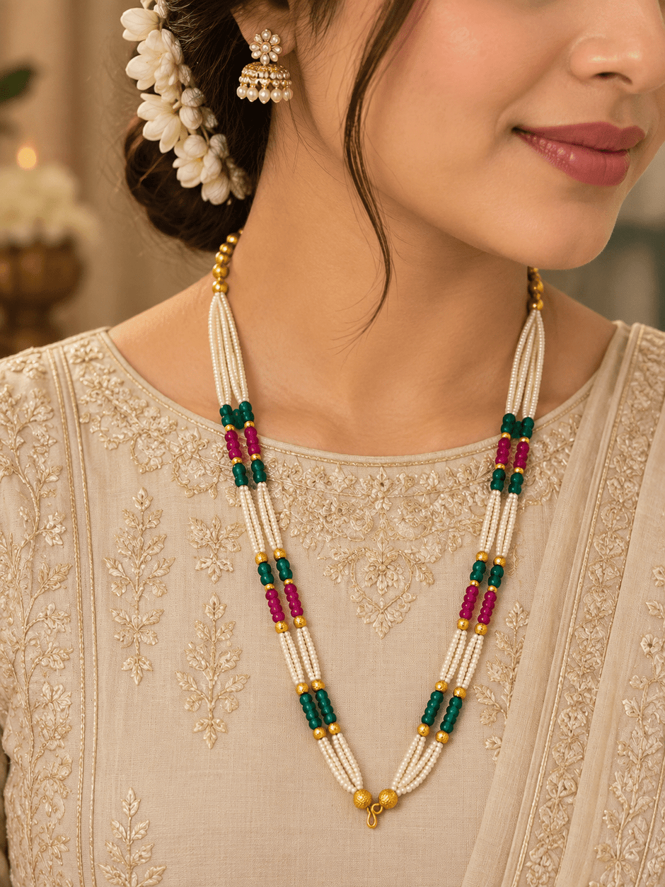 Long multistrand ivory-white pearl-style necklace featuring round gold-tone beads, green and magenta bead sections, and a gold-tone hook clasp, shown from two angles. - bhavmayi